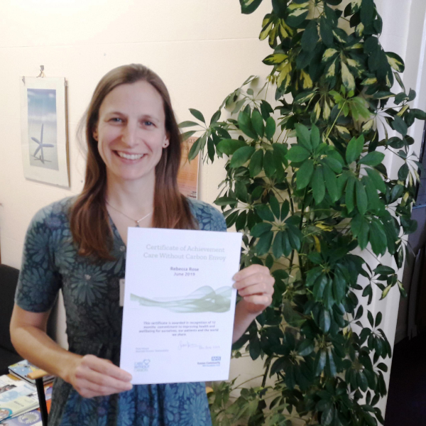 Envoy holding certificate and standing next to a plant